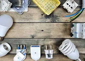 LED-Lampe, Kabel und weiteres Zubeh&ouml;r auf einem Holzbrett. 